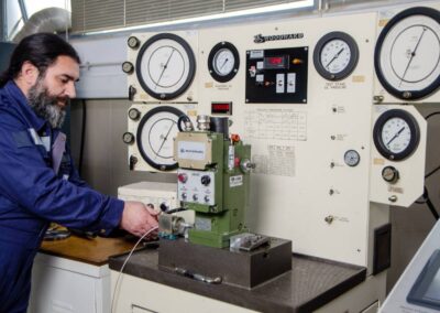 A man technician calibrates a Woodward UG25+ governor on a Woodward test bench.